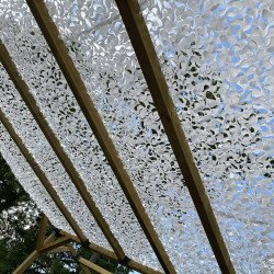 Lumière filtrée par un filet de camouflage blanc sur une pergola en bois