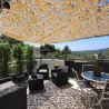 Filet de camouflage beige ombrageant une terrasse avec vue sur les collines