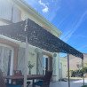 Filet de camouflage noir sur une pergola devant une façade de maison